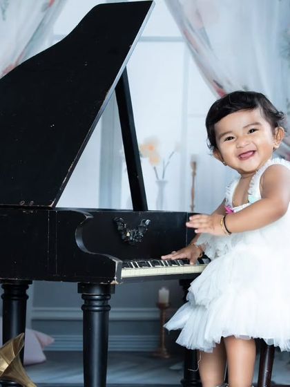 This little pianist is dressed in a lovely white dress, looking angelic as she plays a tune.