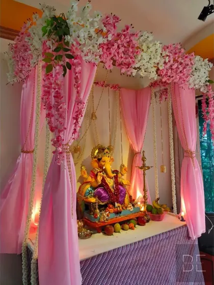 For a soft and elegant look, I designed this pink-themed Ganpati mandap. The setup includes a canopy of pink and white cherry blossoms, flowing pink drapes, and hanging jasmine garlands.