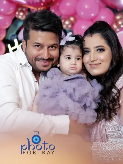 A warm family hug, with the parents and their one year old daughter posing for the camera. This is a classic family portrait from a first birthday photoshoot.