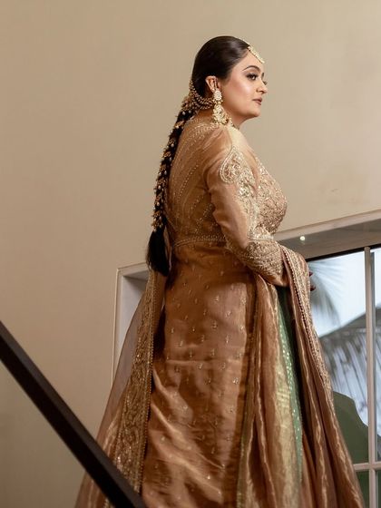 My bride Sachi in a stunning gold and beige outfit, looking regal and elegant. The makeup is soft and sophisticated, with a focus on her eyes.
