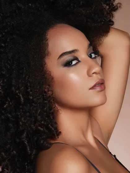 A dramatic, shimmering smokey eye on a model with beautiful curly hair. Our artists learn to work with all skin tones and hair textures to create stunning results.
