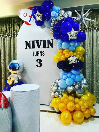 A compact and colorful Space theme setup, perfect for home parties, with a rocket, astronaut, and a vibrant balloon garland.