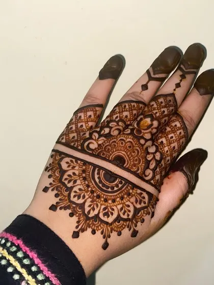 A lovely half-mandala design on the back of the hand, with a clean line separating it from the detailed finger work.