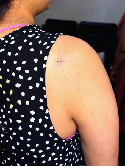 A tiny, three-dot smiley face on the shoulder. This is the ultimate minimalist tattoo, proving that a design doesn't need to be large to bring joy.