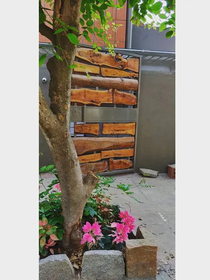 A welcoming entry gate designed with leftover wood pieces from the construction site. Paired with pink poinsettia flowers, this custom detail turns recycled material into a beautiful and sustainable feature.