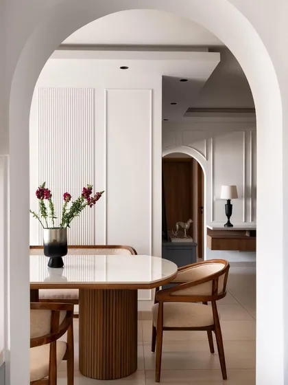 A beautiful arched view into the dining room, highlighting the elegant fluted dining table and classic wall molding. This architectural element was added to create a sense of grace and separation between the living and dining areas.