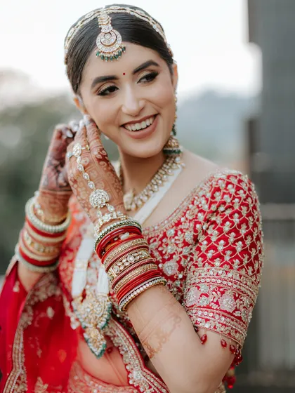 A happy bride is the most beautiful bride! Her hair is pulled back into a classic bun, keeping the focus on her radiant smile and intricate bridal jewellery.