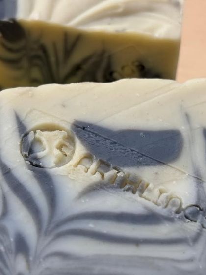 A close-up of the swirl design and our brand stamp on the Charcoal & Dead Sea Mud Soap. We take pride in every detail of our handmade products.