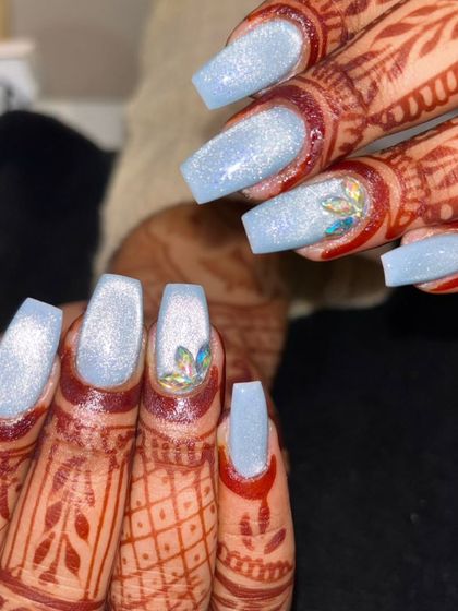 A beautiful contrast of shimmery, sky-blue gel polish against detailed bridal henna. The accent nail features a multi-colored crystal lotus for a unique touch.