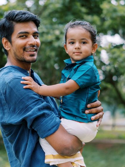 A father holding his son, both dressed in traditional wear. A beautiful way to celebrate culture and family.