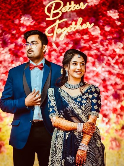 A vibrant couple portrait against a red floral backdrop with a "Better Together" neon sign.