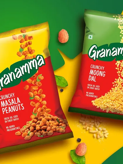 Packaging photography for Granamma's Crunchy Masala Peanuts and Moong Dal. The image uses a vibrant, graphic background with floating ingredients to create a playful and eye catching look for these South Indian snacks.