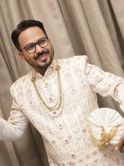The groom holding his turban, showcasing his complete look. The styling is traditional yet fresh, perfect for a modern wedding.