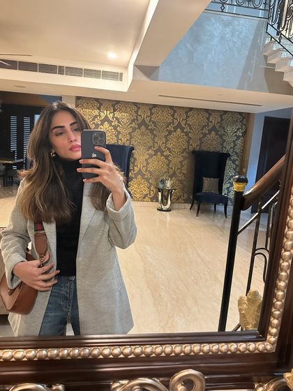 A mirror selfie showing a casual winter look with a grey coat, black turtleneck, and jeans.