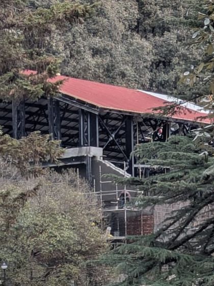 A view of the new structure peeking through the trees, designed to be a sensitive addition to the historic and natural landscape of Landour.