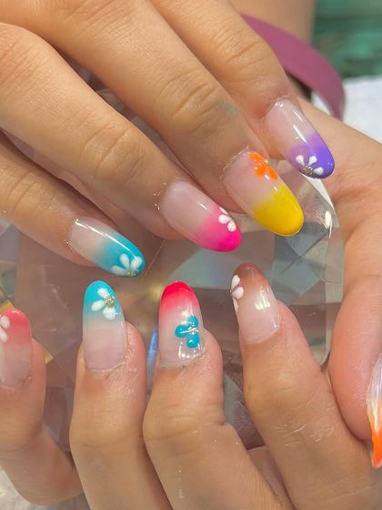 A rainbow of summer fun. These long extensions feature a colorful ombré effect on each nail, adorned with tiny white flowers for the ultimate vacation-ready look.