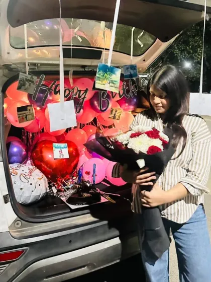 The birthday girl enjoying her car trunk surprise, holding the beautiful bouquet that was part of the decoration.