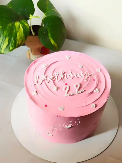 A simple and sweet pink cake with "birthday 22" written in a delicate script. The spiral top and tiny hearts add a touch of charm to this minimalist design.