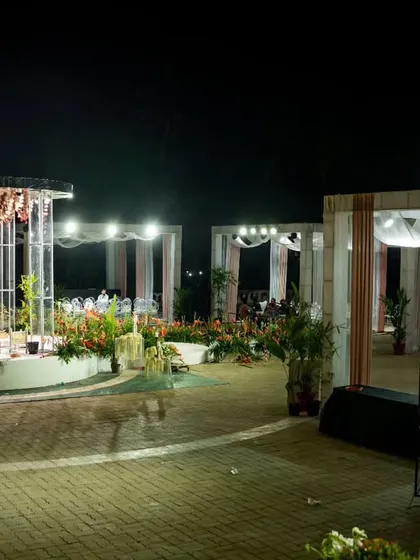 A glowing wedding night in a garden setting. The mandap, lit by a grand chandelier, and the surrounding draped cabanas create a romantic and dreamy atmosphere under the stars.