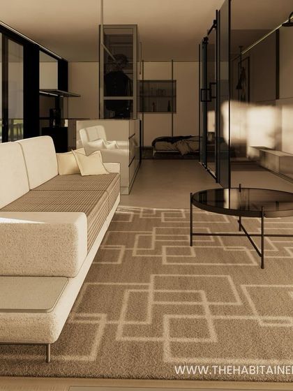 Another view of the living area in the container studio, showcasing the sophisticated furniture and geometric rug.