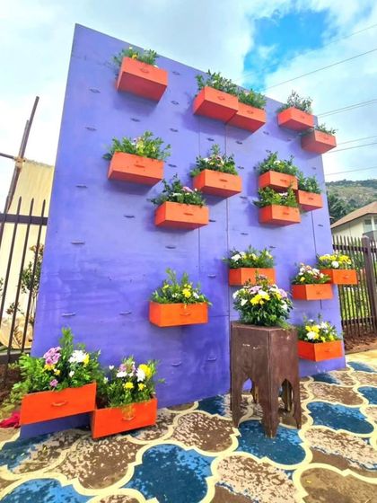 A unique and colorful photo wall. The purple wall is adorned with orange drawers filled with flowers, creating an interactive and artistic backdrop.
