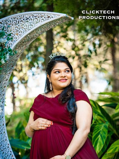 A happy solo maternity portrait with a crescent moon prop in the garden.