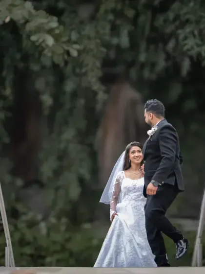 A wide shot of the couple in a park setting, creating a sense of a private, shared moment in the midst of nature.