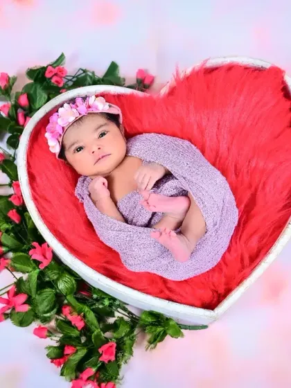 A newborn nestled in a heart-shaped basket surrounded by flowers. This setup is perfect for celebrating the love a new baby brings.
