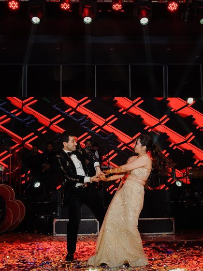 The couple's first dance at their sangeet. Captured mid-twirl on a confetti-covered stage, this photo is full of energy, movement, and joy.