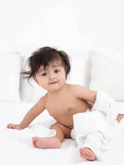 A mischievous look from a baby playing on the bed. I love capturing all the different facets of their budding personalities.