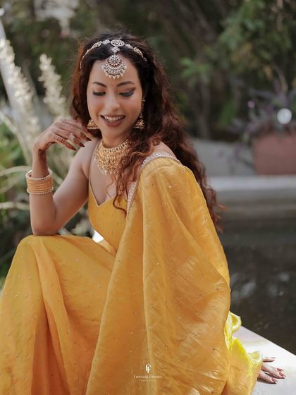 The bride, adorned in a stunning yellow lehenga and floral jewelry, smiles during her Haldi ceremony. This portrait highlights her radiant beauty.