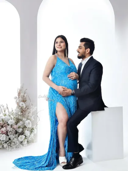 A glamorous studio portrait of an expecting couple. The mom-to-be shines in a sparkling blue gown, and the loving gaze between them is perfectly captured.