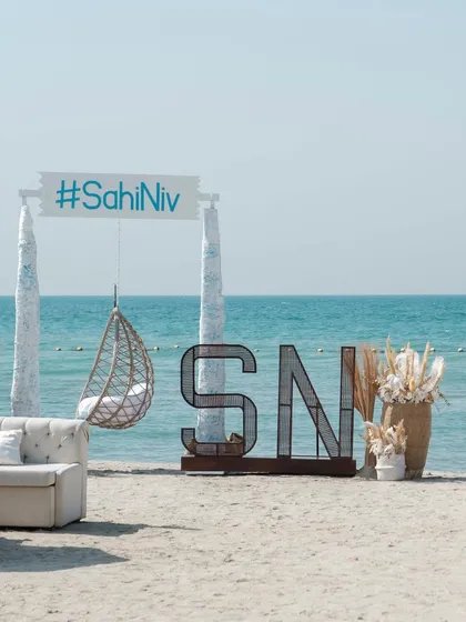 A chic beachside setup with a custom sign featuring the couple's wedding hashtag. This creates a perfect, branded photo opportunity for guests.