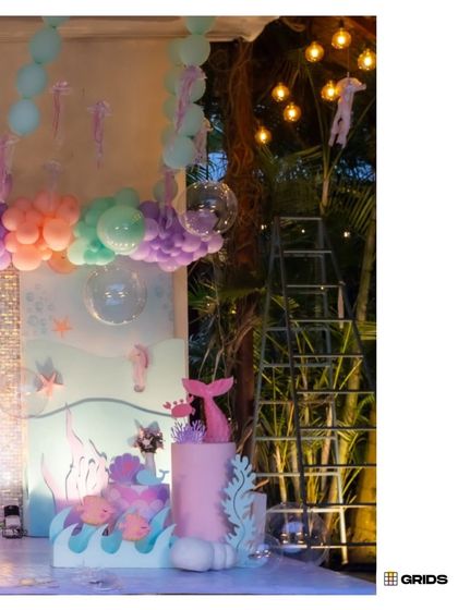 A side view of the mermaid party setup at night, with hanging lights and illuminated props creating a magical, glowing effect.