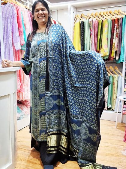 Another view of me in my favorite Ajrakh kurti, showcasing the beautiful drape of the fabric. You can see the variety of ready-made and unstitched options available in the background.