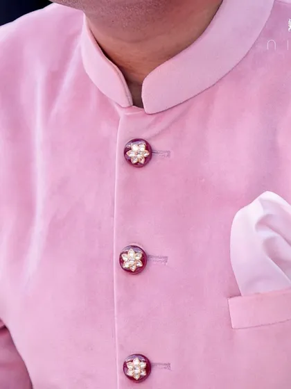 For our client's Tika ceremony, we designed this elegant pink velvet sherwani. The custom jeweled buttons add a touch of bling, making it a truly special occasion piece.