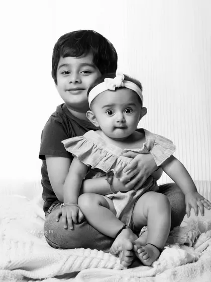 Sometimes, the most powerful portraits are the simplest. This classic black and white sibling photo focuses on the pure, loving connection between a big brother and his baby sister.