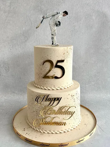 The full view of the elegant two-tiered cake we created for Shubman Gill's 25th birthday, featuring a speckled buttercream finish and gold accents.