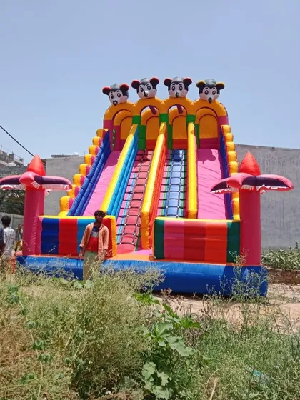 This is my giant Mickey Mouse themed inflatable slide, standing tall at 18x26 feet. The person standing next to it shows just how big and impressive it is, making it a guaranteed centerpiece for any large event or mela.
