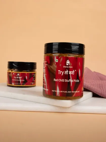 Jars of Red Chilli Stuffed Pickle presented on a marble slab, with simple styling to keep the focus on the product.