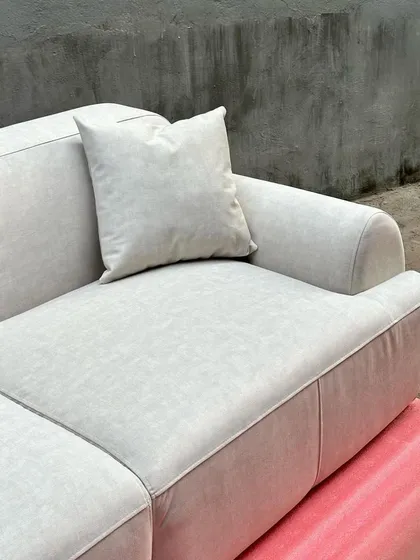 A close-up detail of a modern, minimalist sofa with plush, comfortable cushions in a light, neutral fabric.