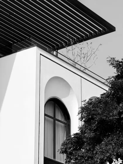 An architectural detail study of an arched window. We believe in the poetry of form, and this monochrome shot captures the timeless elegance of the arch, a recurring motif in our modern-classical designs.