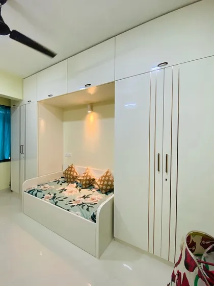 A space-saving bedroom design featuring a daybed nestled within a full wall of white wardrobes. This is an ideal solution for a guest room or a smaller bedroom to maximize floor space.
