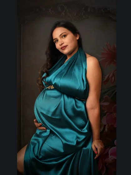 A classic portrait pose in a beautiful teal satin gown. The focus is entirely on the mom-to-be and her radiant pregnancy glow.