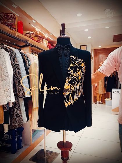 A mannequin displaying a black tuxedo jacket with a gold hand-painted lion on the lapel. This is a bold and regal design for someone looking to command attention.