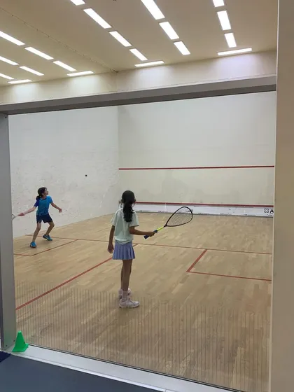 Two young female athletes compete in a spirited match during the Willingdon Squash Academy tournament.