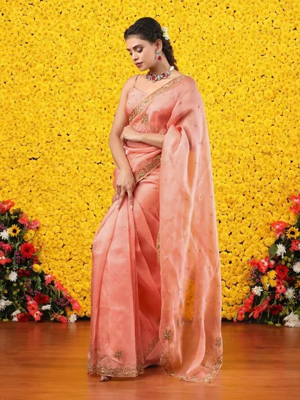 The full, standing view of the peach organza saree, a picture of sophistication and grace.