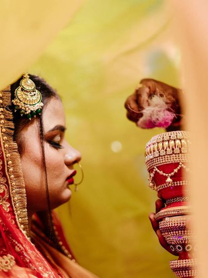 Framed through the bride's veil, this shot offers an artistic perspective on the Sindoor Daan ceremony. The soft focus and warm tones add to the sacred and intimate feel of this pivotal wedding ritual.