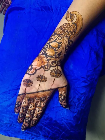 A practice piece focusing on florals and ornamentation. This design features a large, graceful peacock on the arm, with delicate lotus buds hanging below.