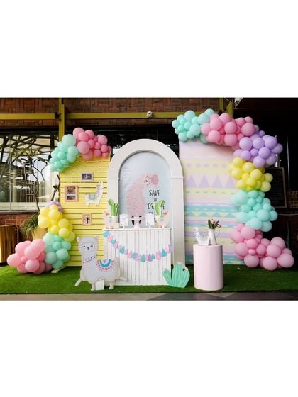 A fun and colorful Llama-themed party setup. The backdrop features pastel colors, cactus props, and a cute llama garland.